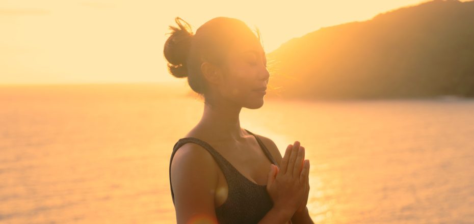 Silhouette of Asian woman improves balance for body, mind and spirit with yoga practice at sunset on the beach. Slow movements and deep breathing improves strength and flexibility. mental health